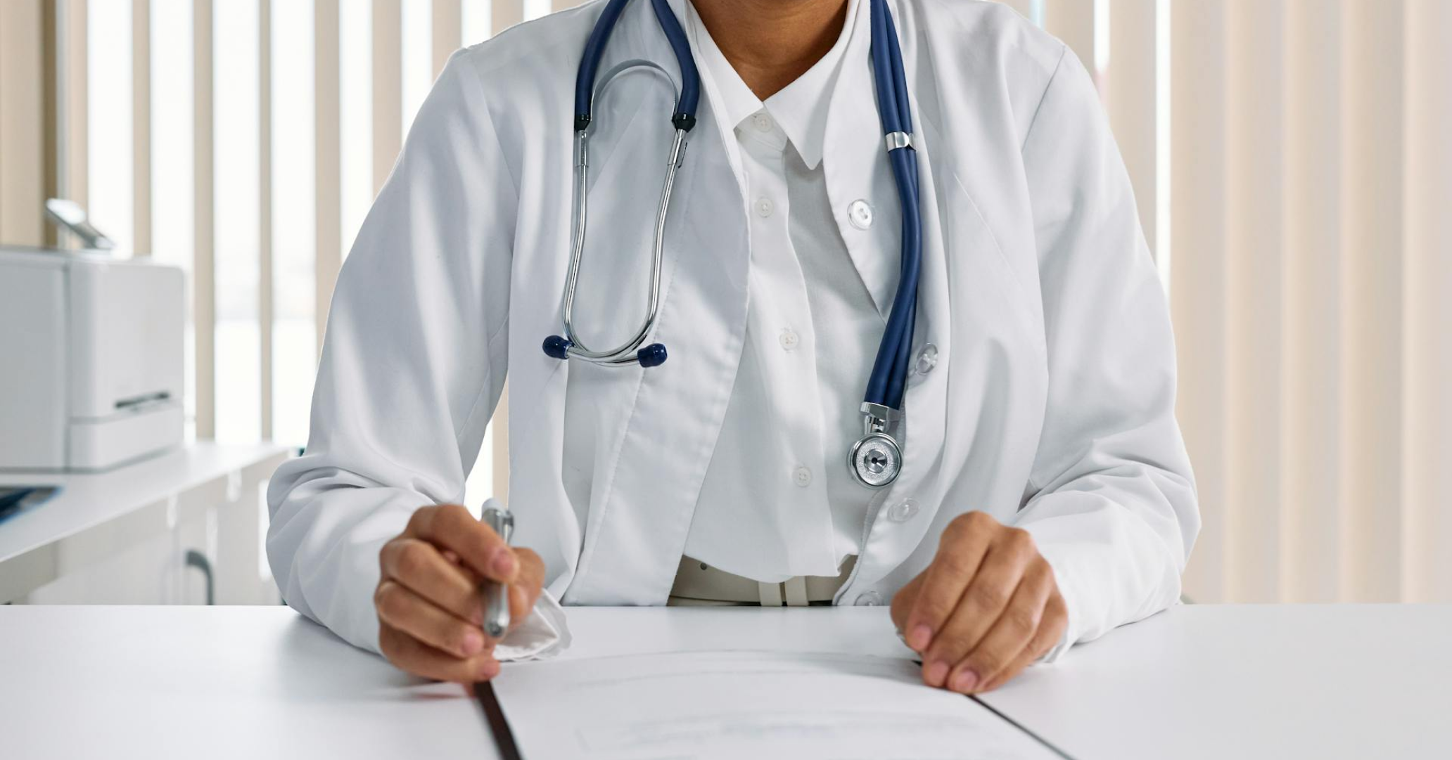 Image of a doctor sitting at a desk. TrueCost group uses respond.io to connect customers across the US with reputable health and dental service providers.